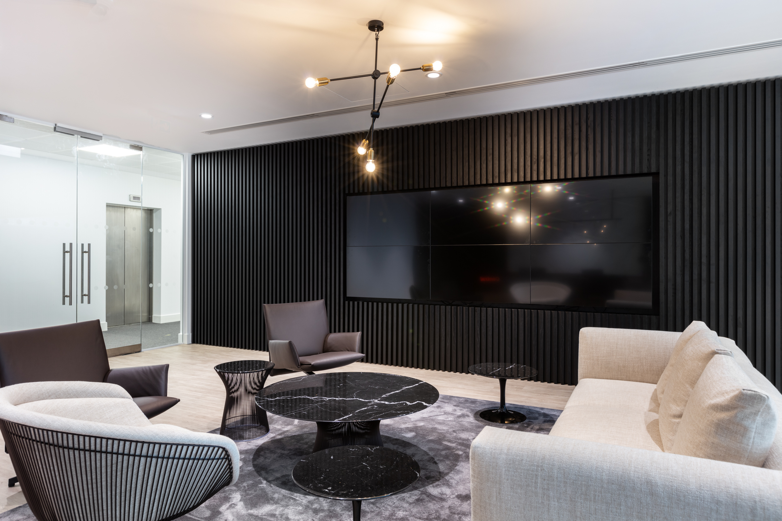 Meeting rooms with patterned glass partitions, offering a touch of privacy while maintaining an open-plan feel. The geometric design adds a modern aesthetic to the office layout.