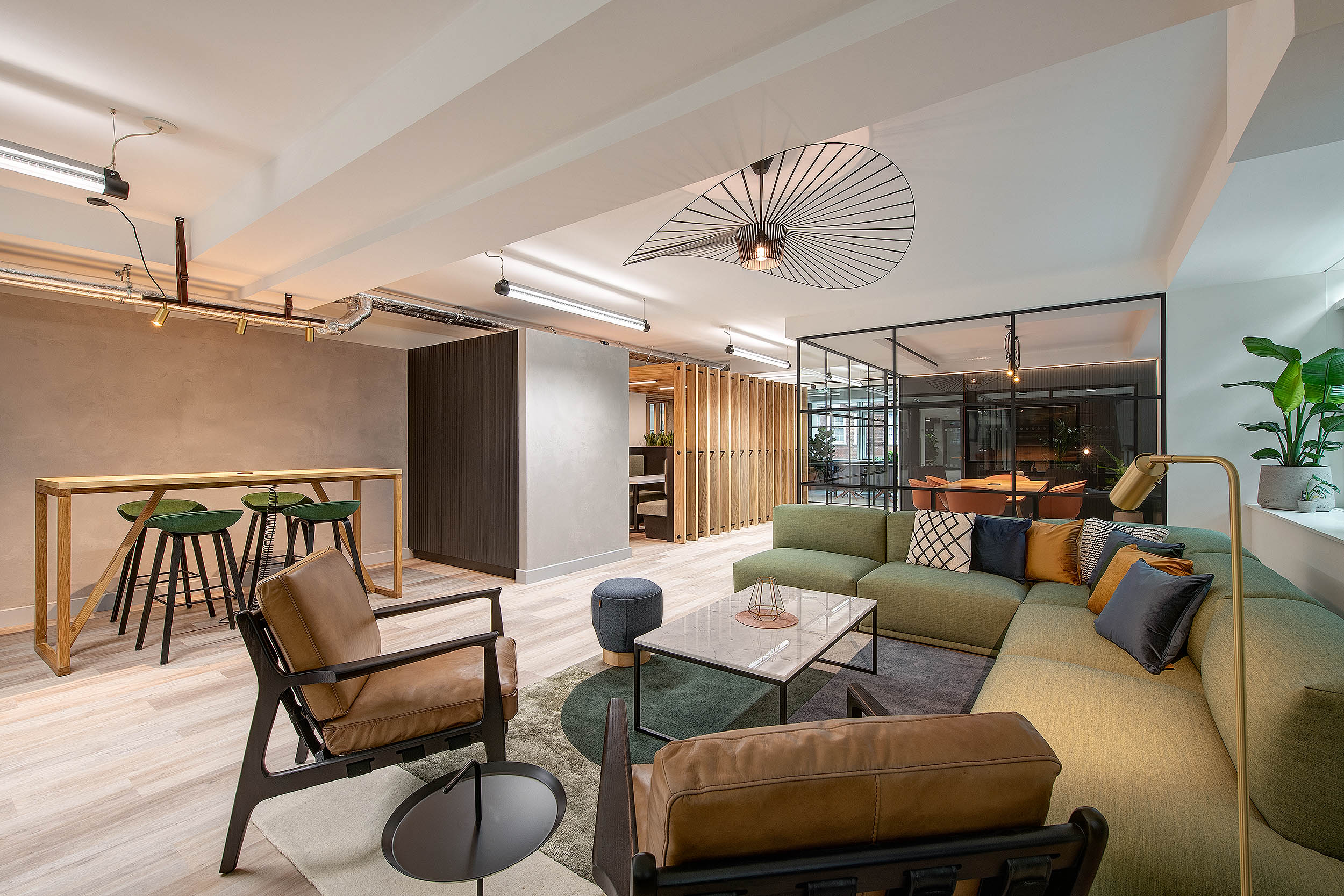 101 New Cavensdish St featuring a green sofa, glass meeting room, and burnt oranges and brown colour palette.