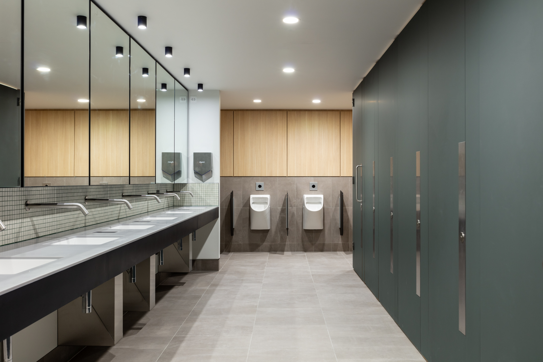 A sophisticated restroom area in Chiswick Business Park with modern sinks, wooden partitions, and minimalist lighting.
