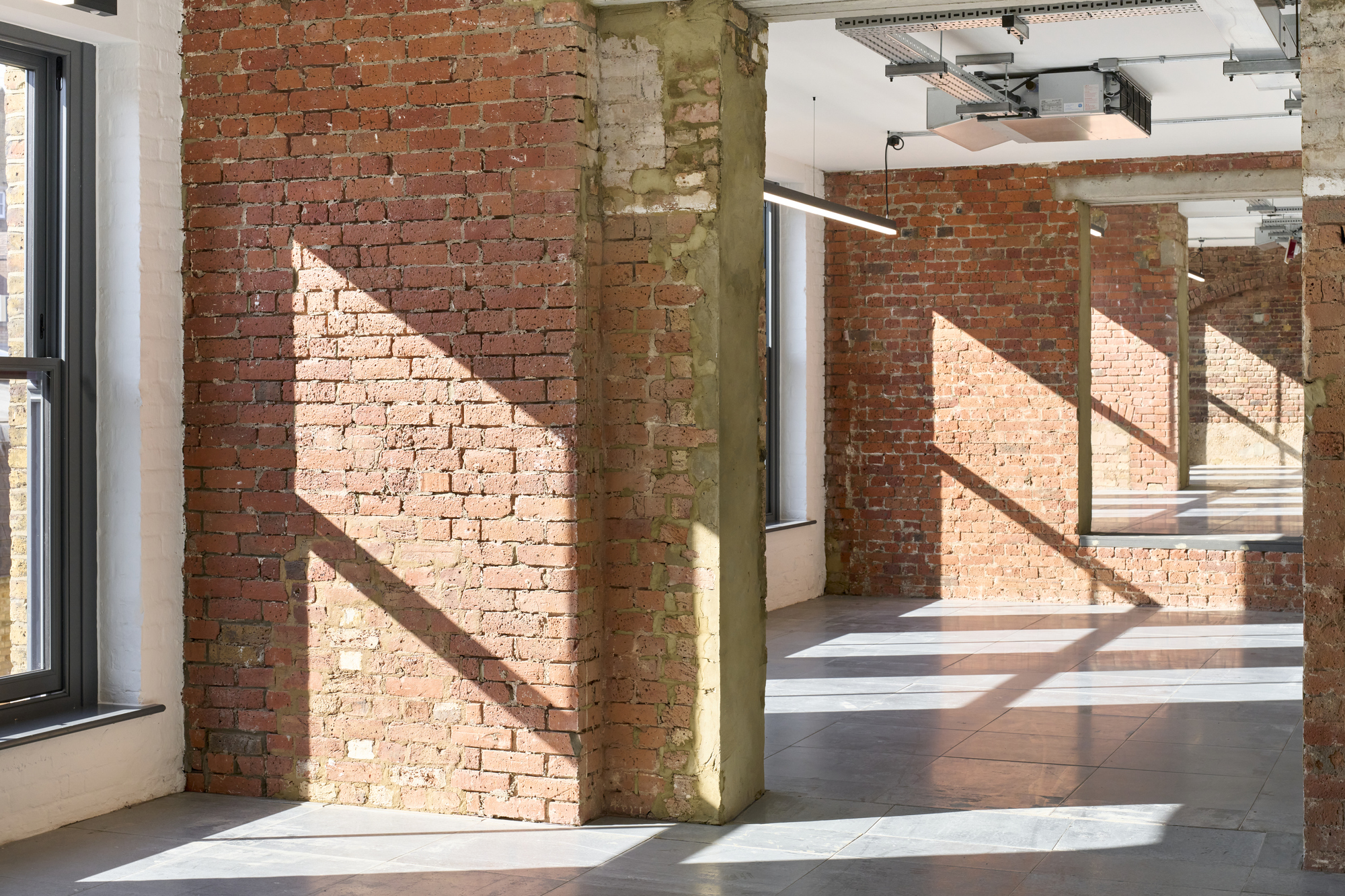 Ambit The Waterman exposed brick space, with large windows creating a bright and open workspace.