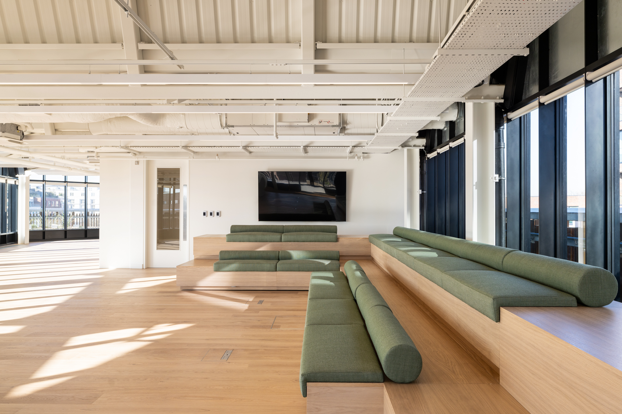 AMBIT LabTech open workspace featuring light white walls, a large screen and large windows.