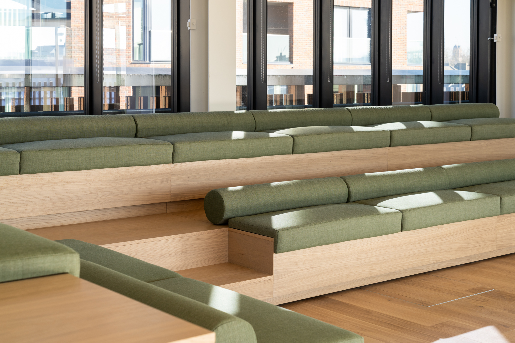 AMBIT LabTech sage green soft seating area, contrasted with light oak layered seating, and large glass windows