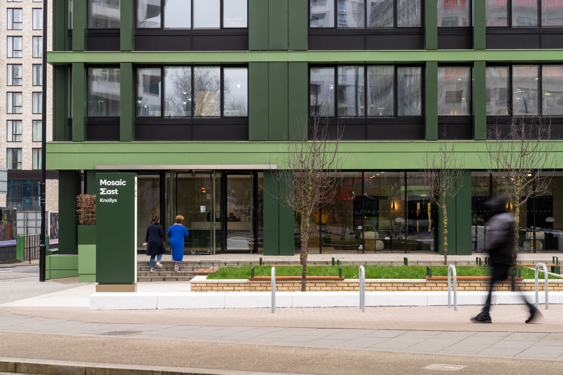 The revitalised entrance of Mosaic East, featuring bold green cladding, modern landscaping, and a welcoming reception space.