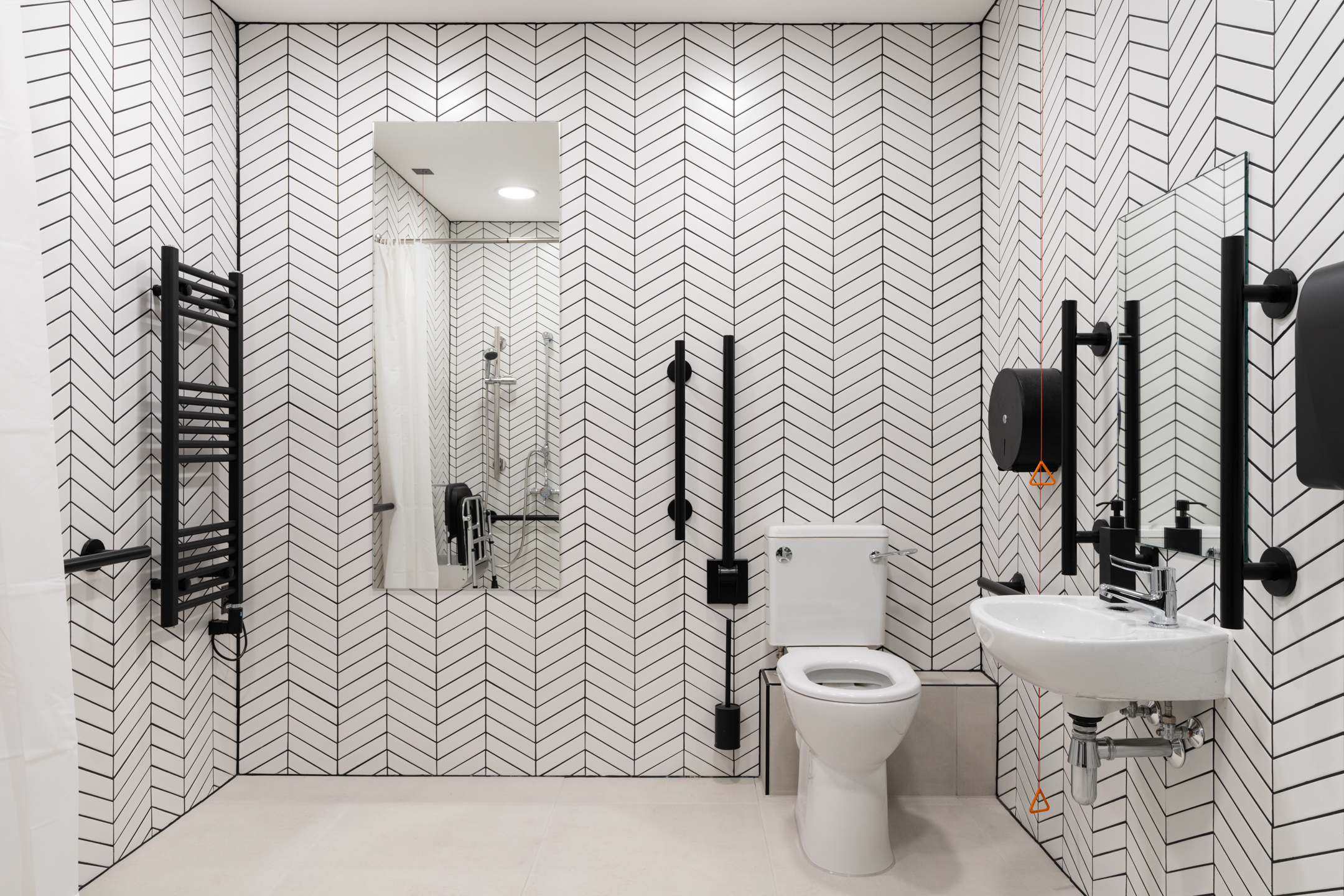 A modern, fully accessible bathroom with a sleek monochrome design, featuring grab rails, a spacious layout, and stylish finishes.