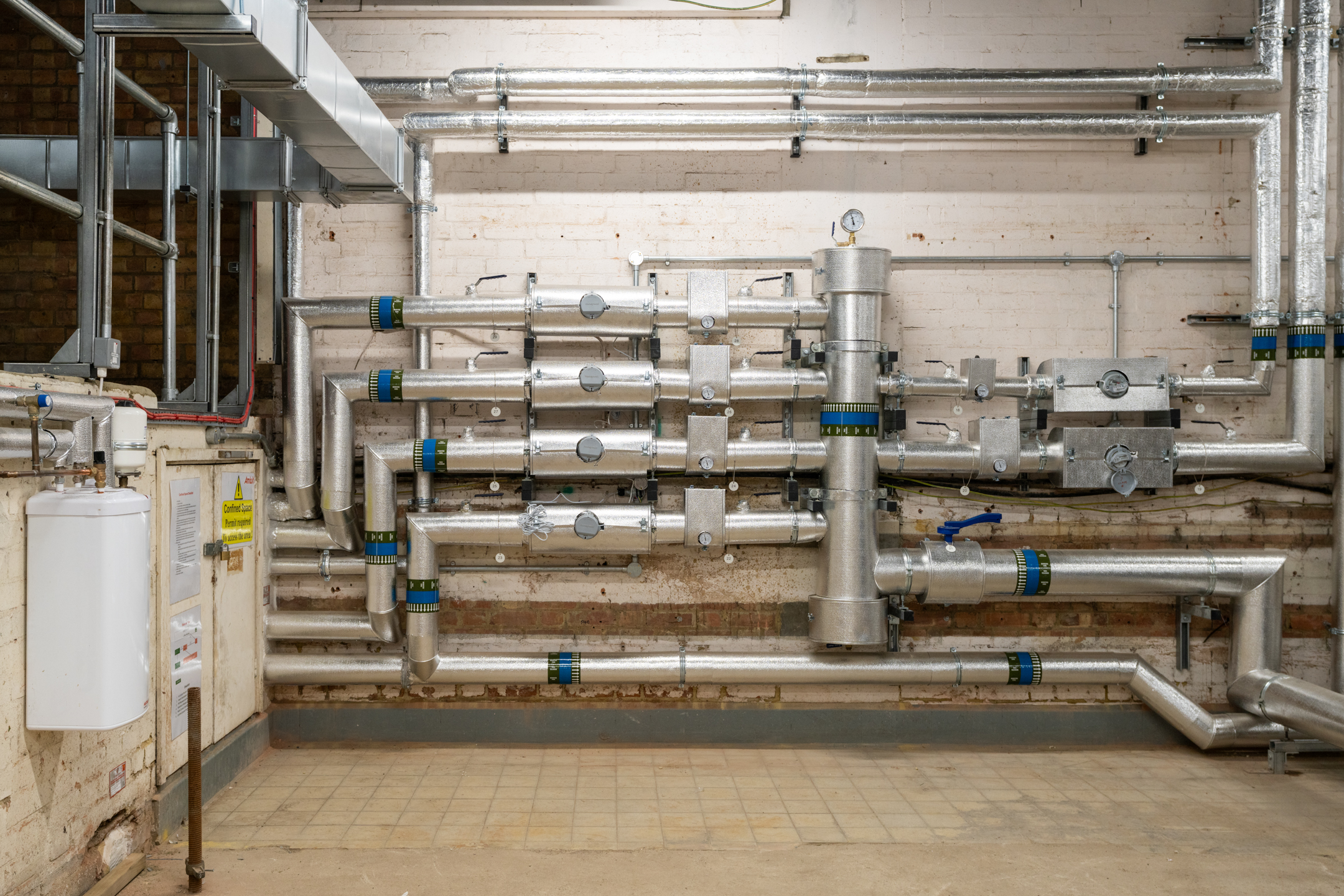 A look inside the upgraded basement plant room at Mosaic East, showcasing new energy-efficient pipework and mechanical systems.