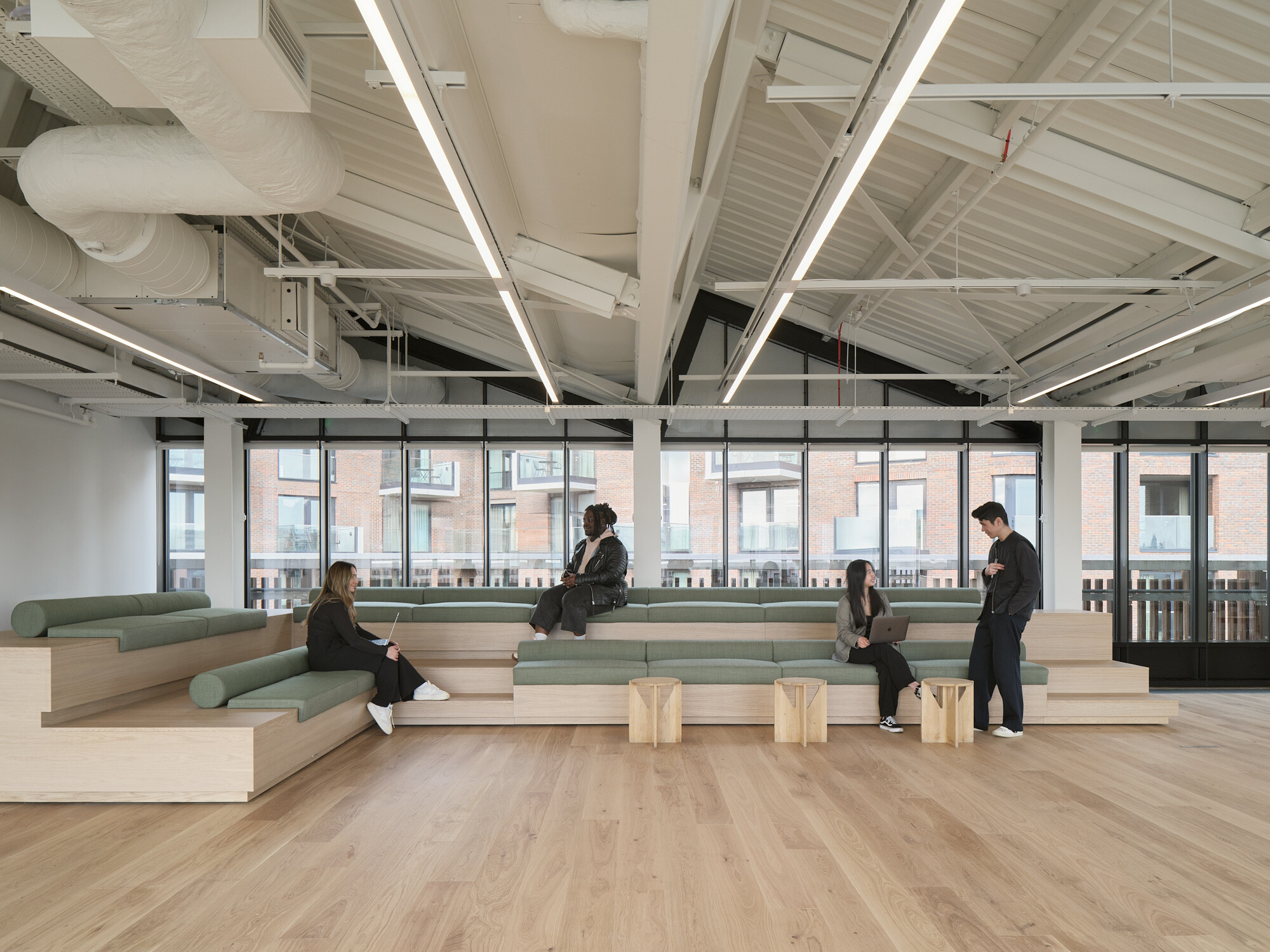 Tiered seating area at Labtech’s Hawley Wharf, designed for informal meetings and town halls, with soft green upholstery and exposed ceiling infrastructure.