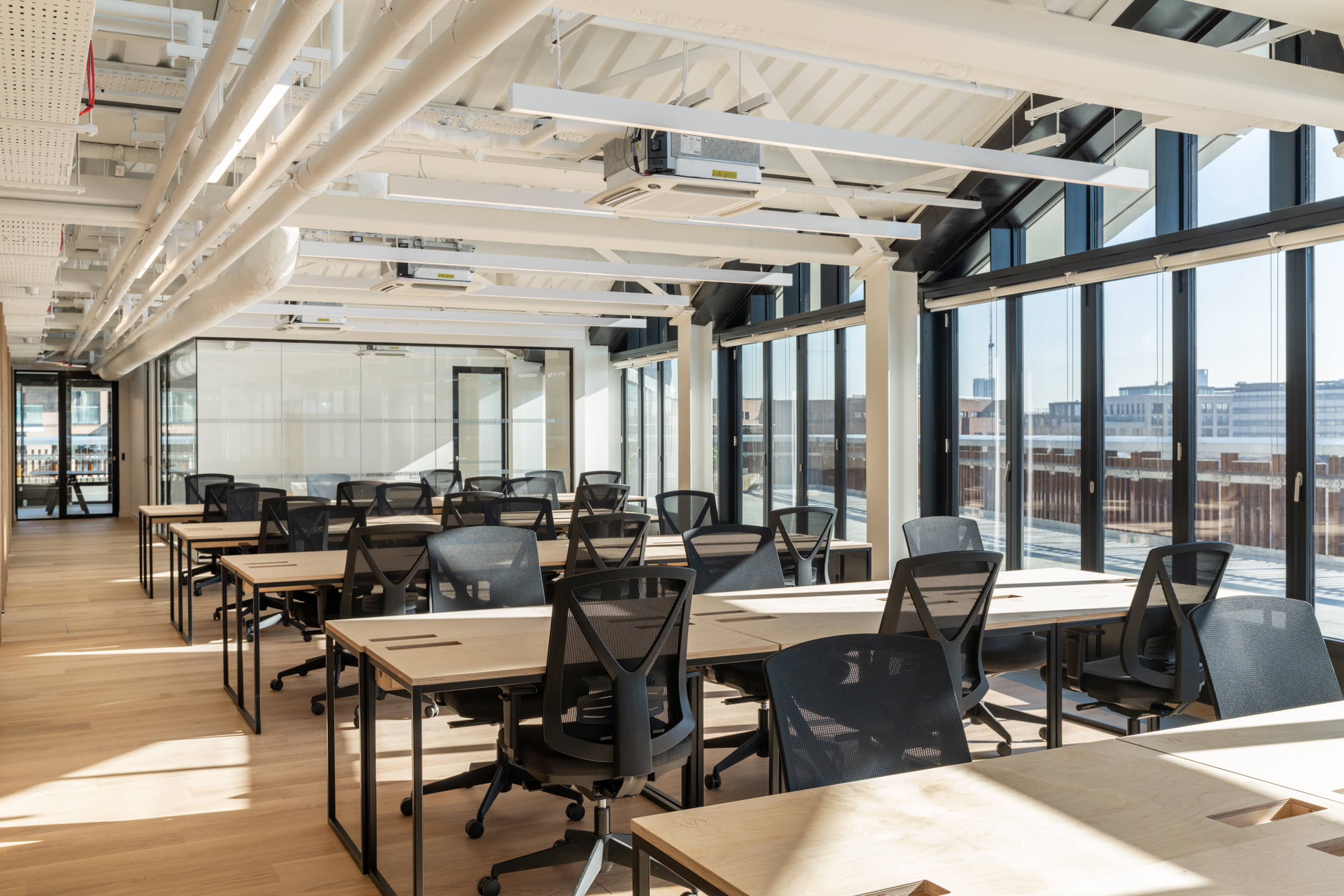 Light-filled open plan office at Labtech’s Hawley Wharf with rows of desking, mesh task chairs and full-height glazing overlooking Camden.