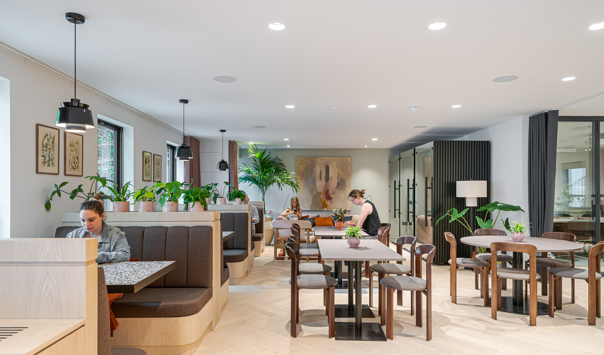 Warm, inviting work reception lounge at Bloomsbury House with integrated booth seating, soft lighting, greenery and artwork, offering flexible spaces for focused work and informal collaboration.