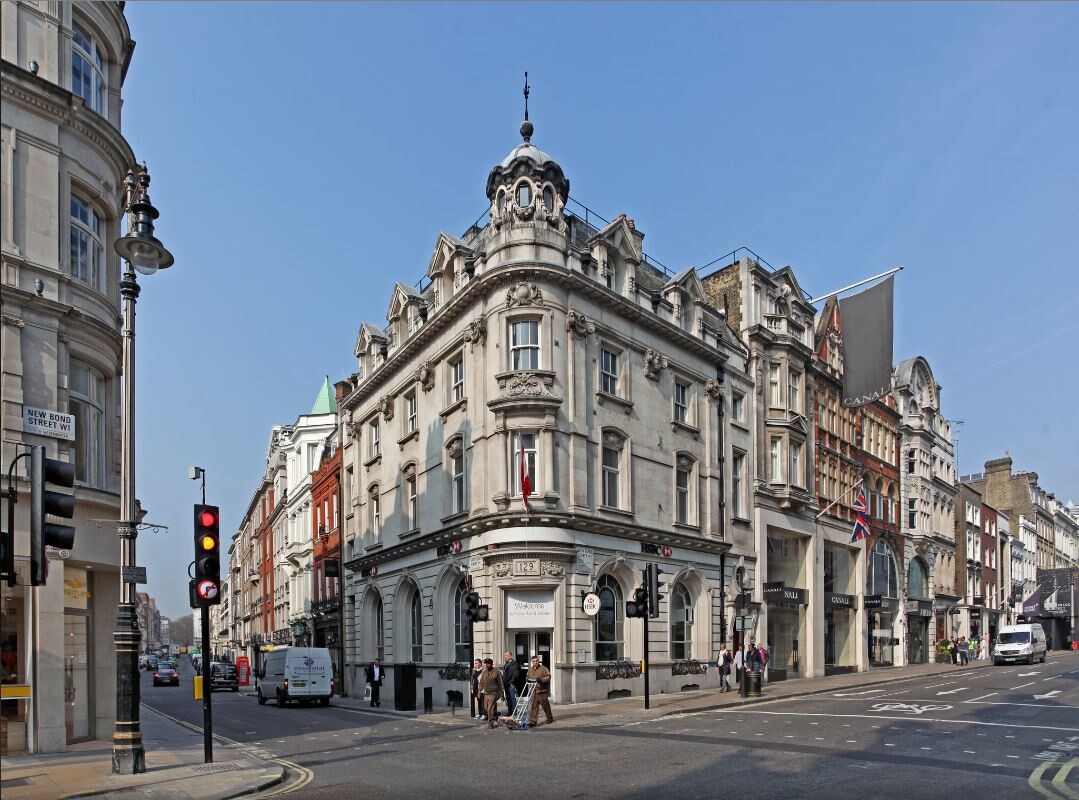 Street view of 128–129 New Bond Street, a prominent corner building in Mayfair with ornate stone façades and period architecture, marking Ambit's latest refurbishment win.