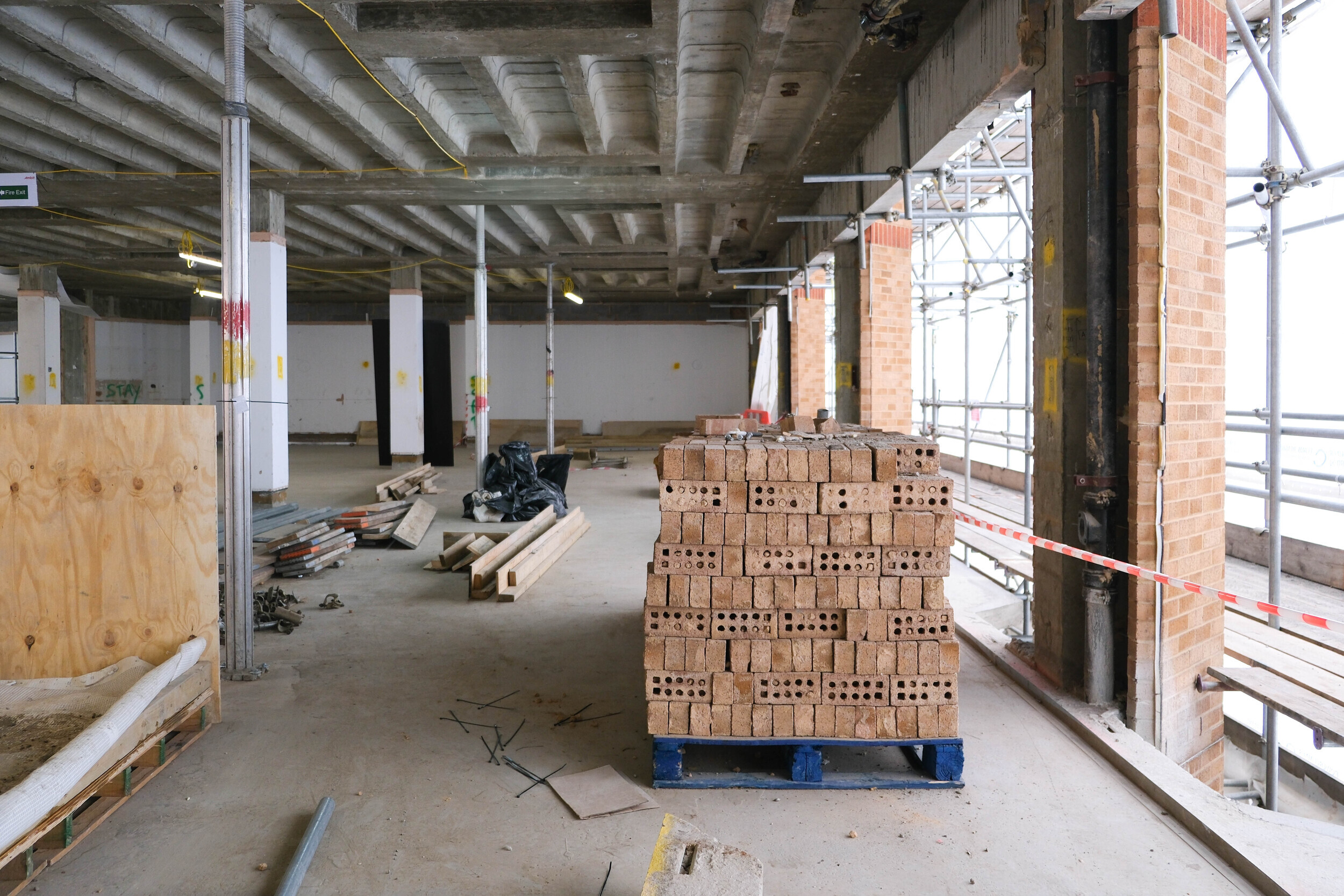 Pallet of reclaimed bricks stacked in the centre of an indoor construction area, part of the Rochester Row Recycling Reused Bricks project.
