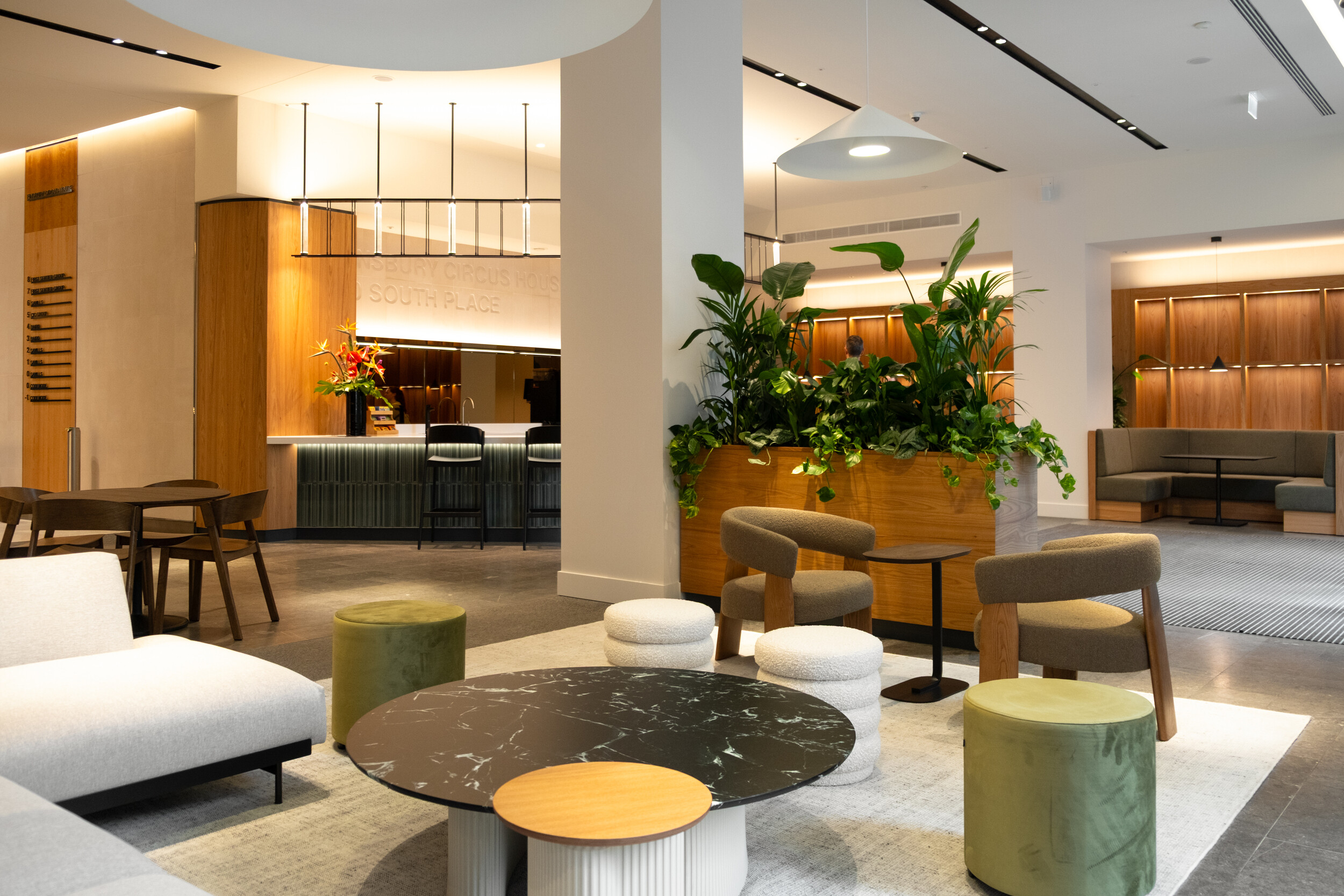 Reception area at Finsbury Circus House with contemporary lounge seating, lush planting, and a wood-panelled backdrop.