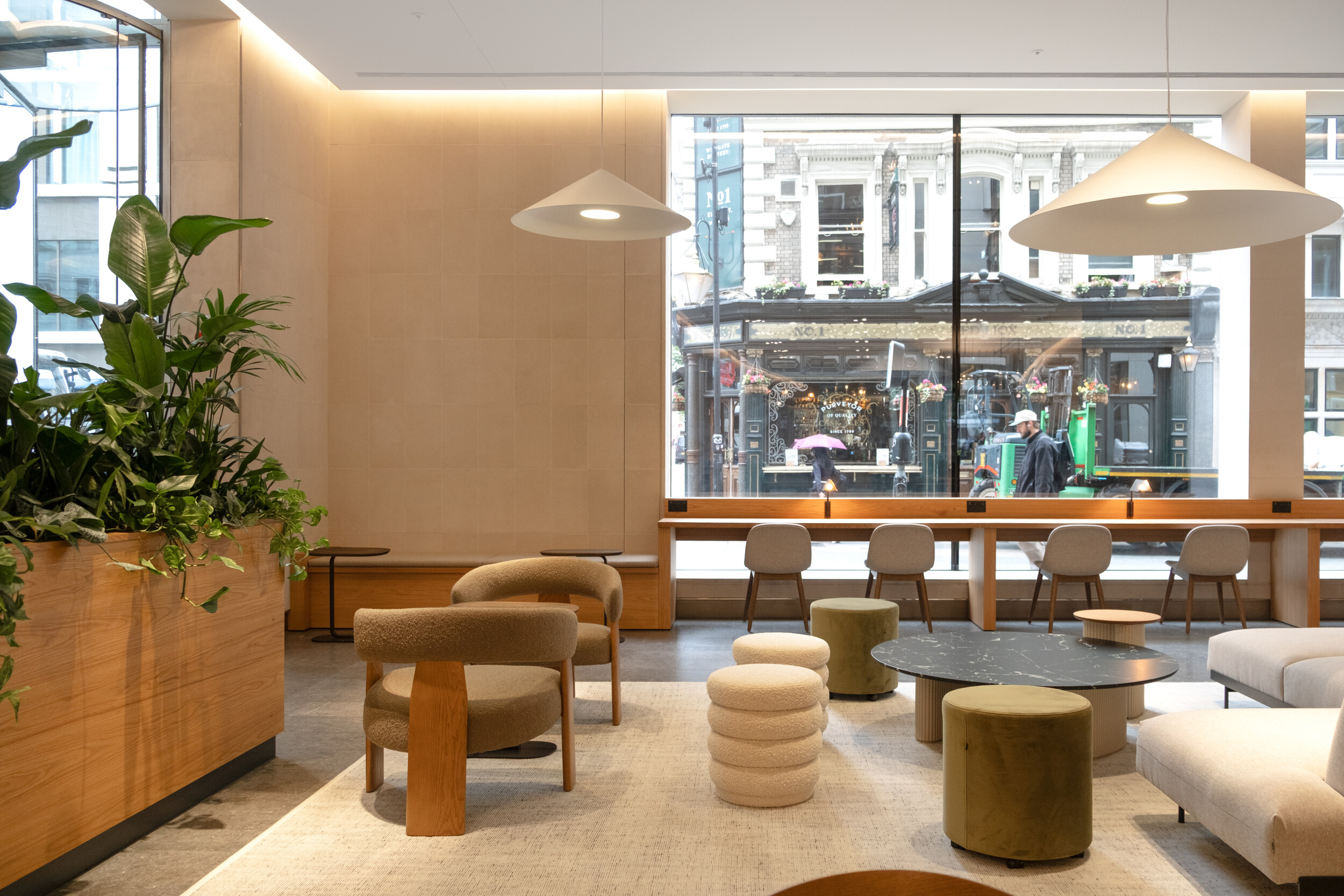 Street-facing lounge space at Finsbury Circus House with a mix of soft seating, high stools, and planting.