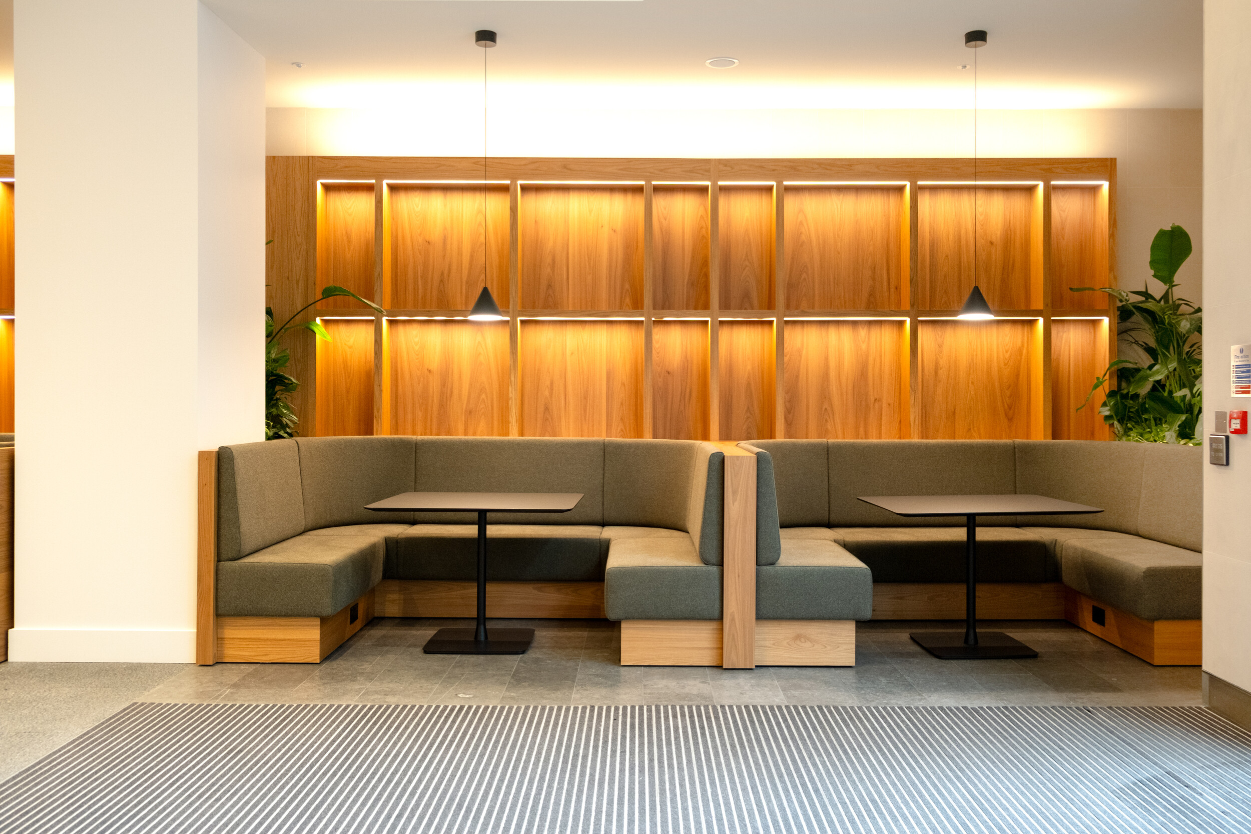 Bespoke booth seating at Finsbury Circus House, set against a timber-panelled wall with integrated lighting.