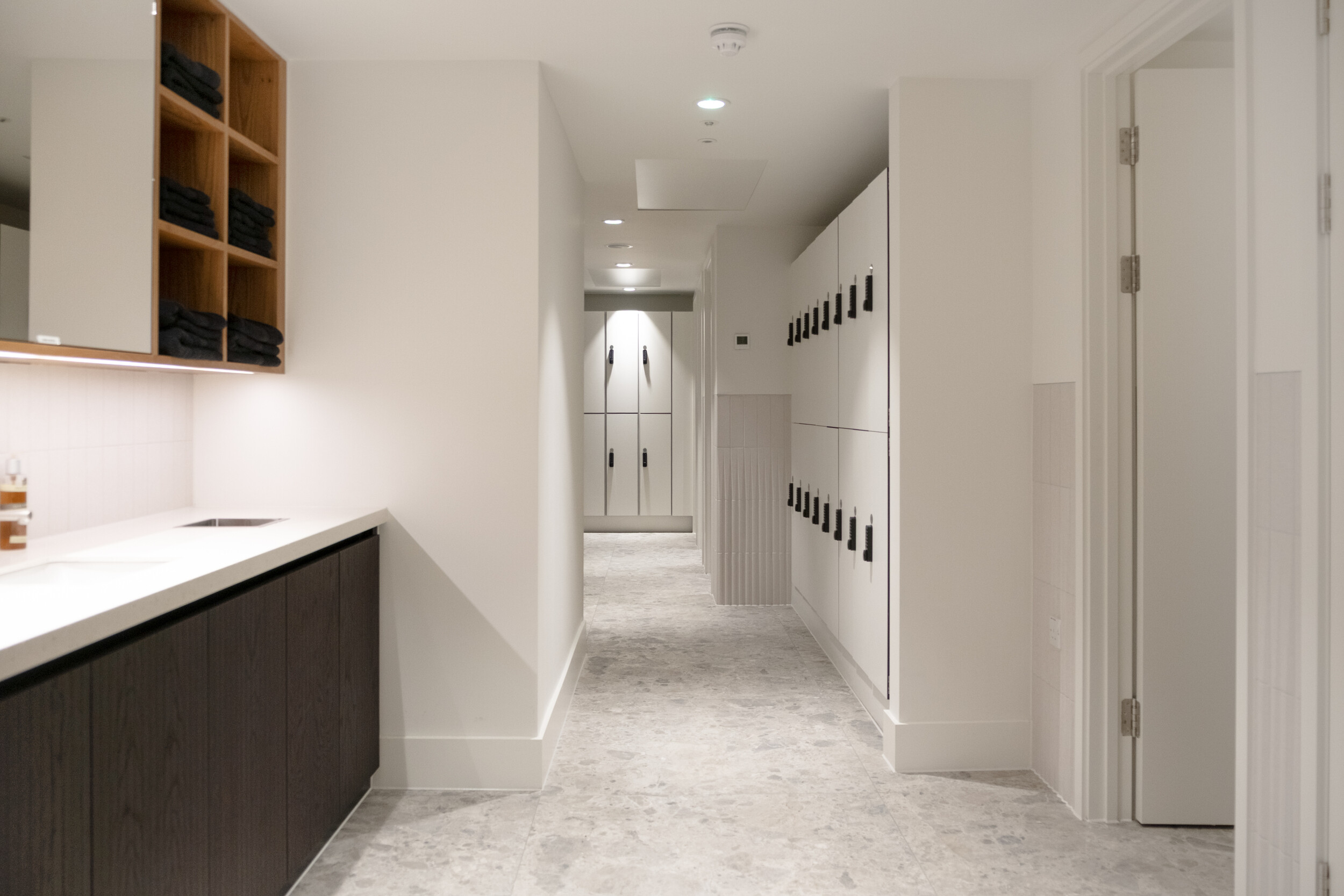 Refurbished lower ground locker room at Finsbury Circus House with modern cabinetry, towel storage, and soft neutral finishes.